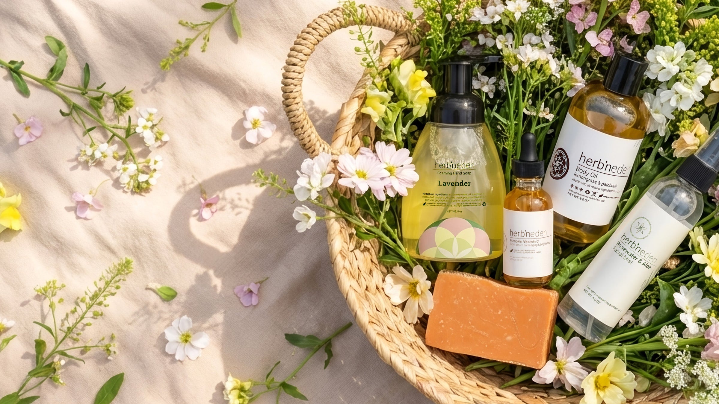 A group shot of products that are recommended for Springtime in a basket, surrounded by flowers in a picnic setting. 